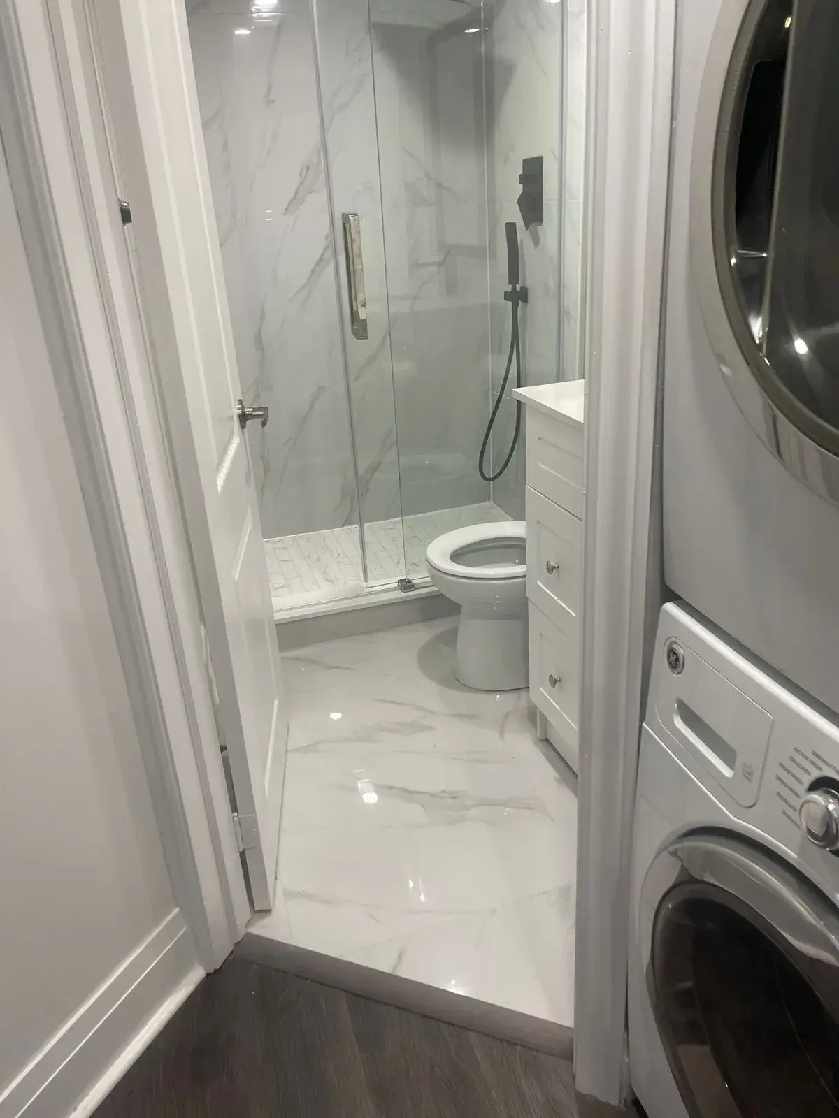 Finished basement bathroom with a glass shower and laundry area