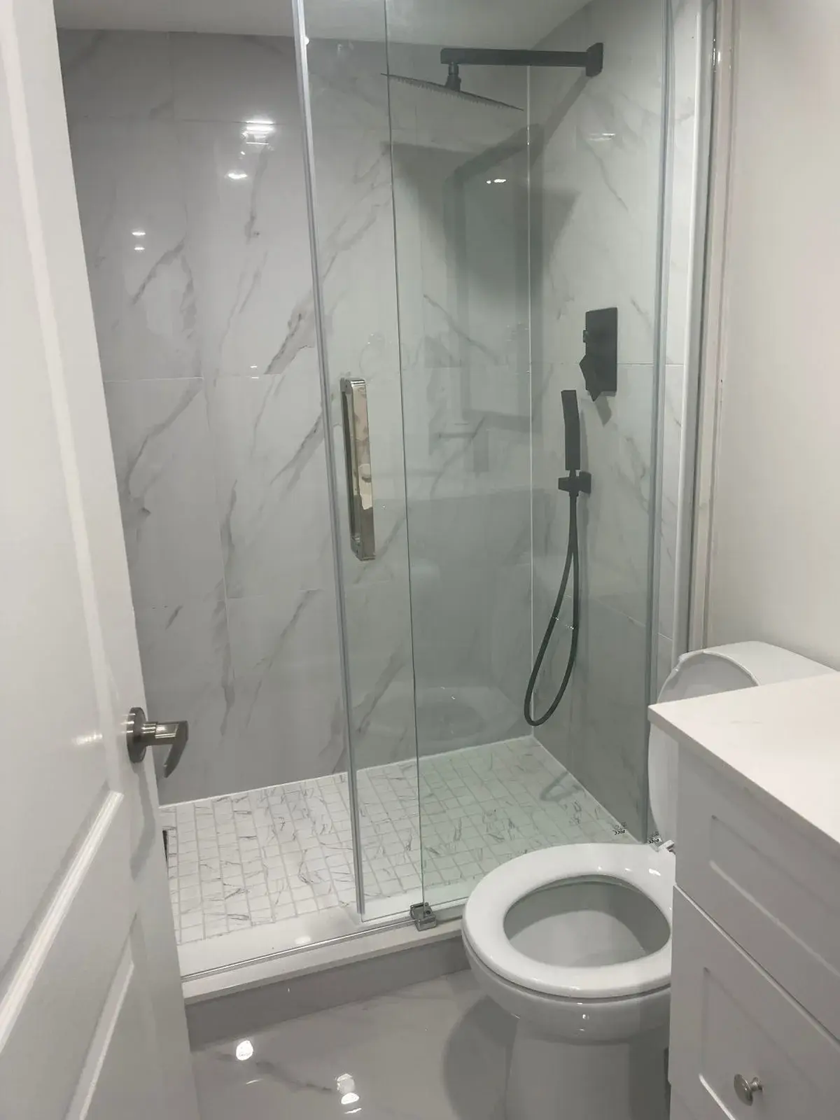 Renovated bathroom with a glass walk-in shower and marble-look porcelain tile