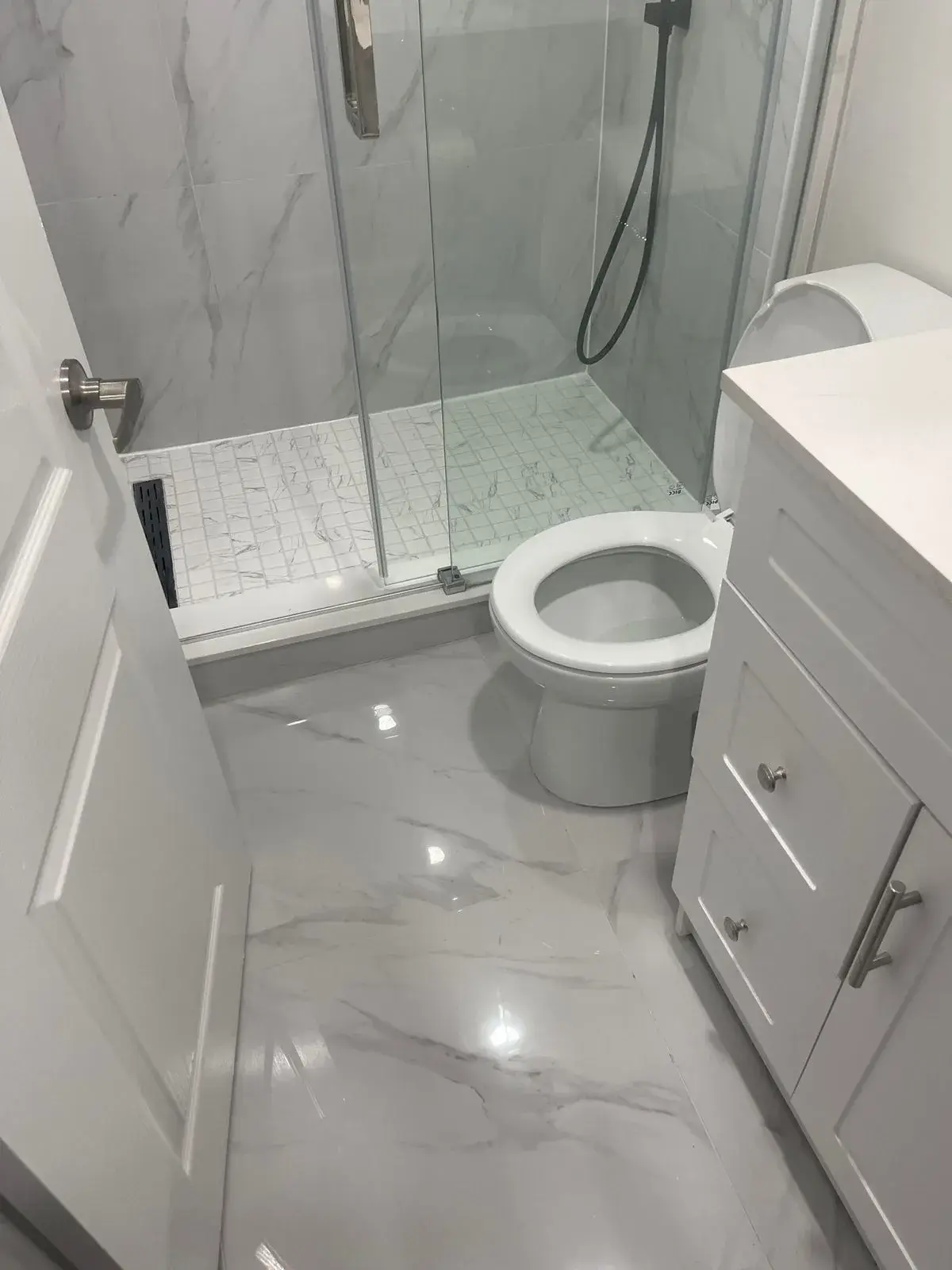 Polished marble-look porcelain bathroom floor beside a glass shower