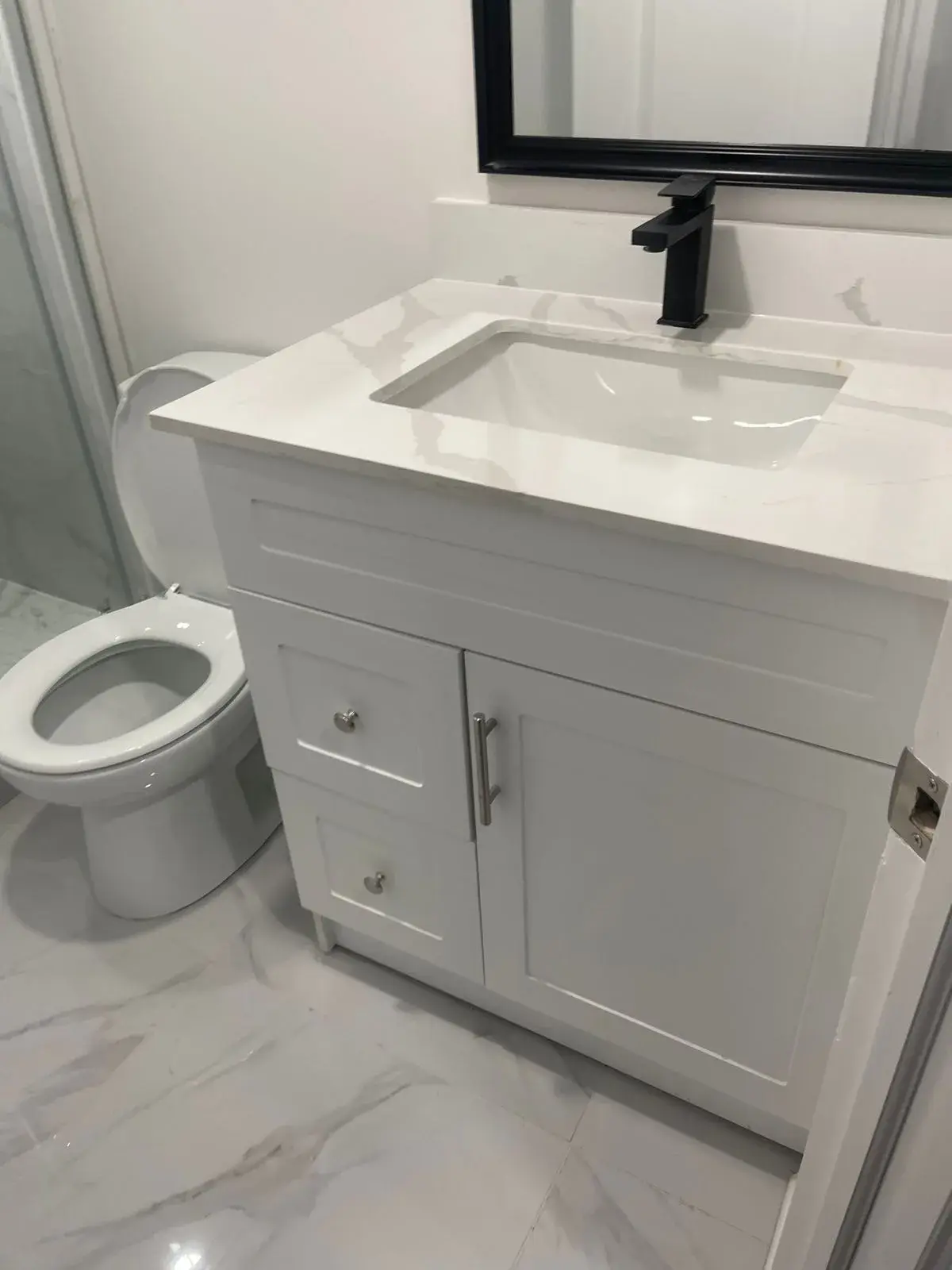 White shaker vanity with a quartz top and black faucet