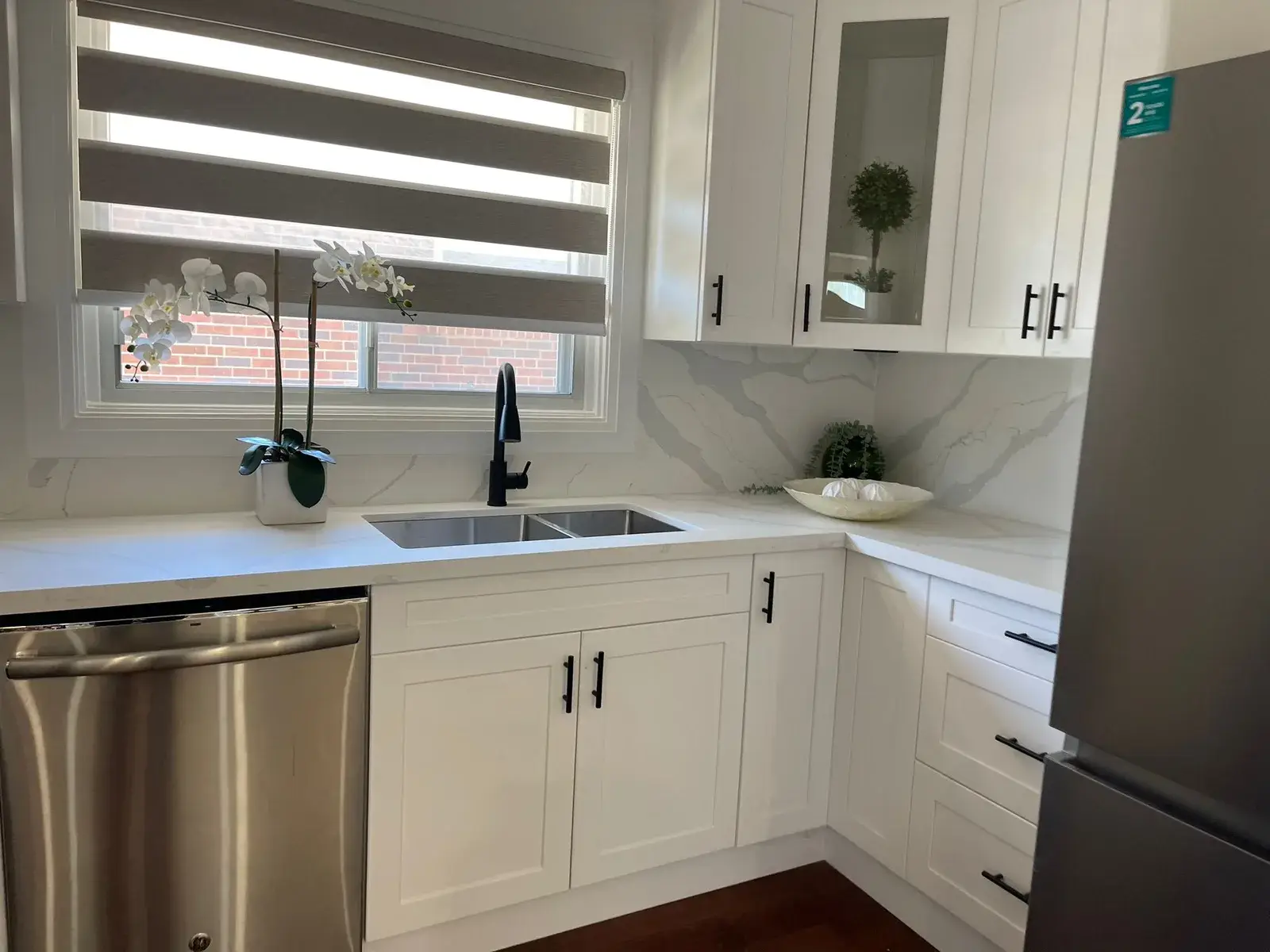 White shaker kitchen with quartz countertops and a black faucet