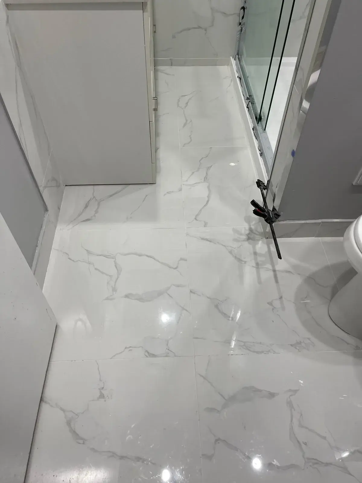 Large-format marble-look porcelain tile floor in a bathroom