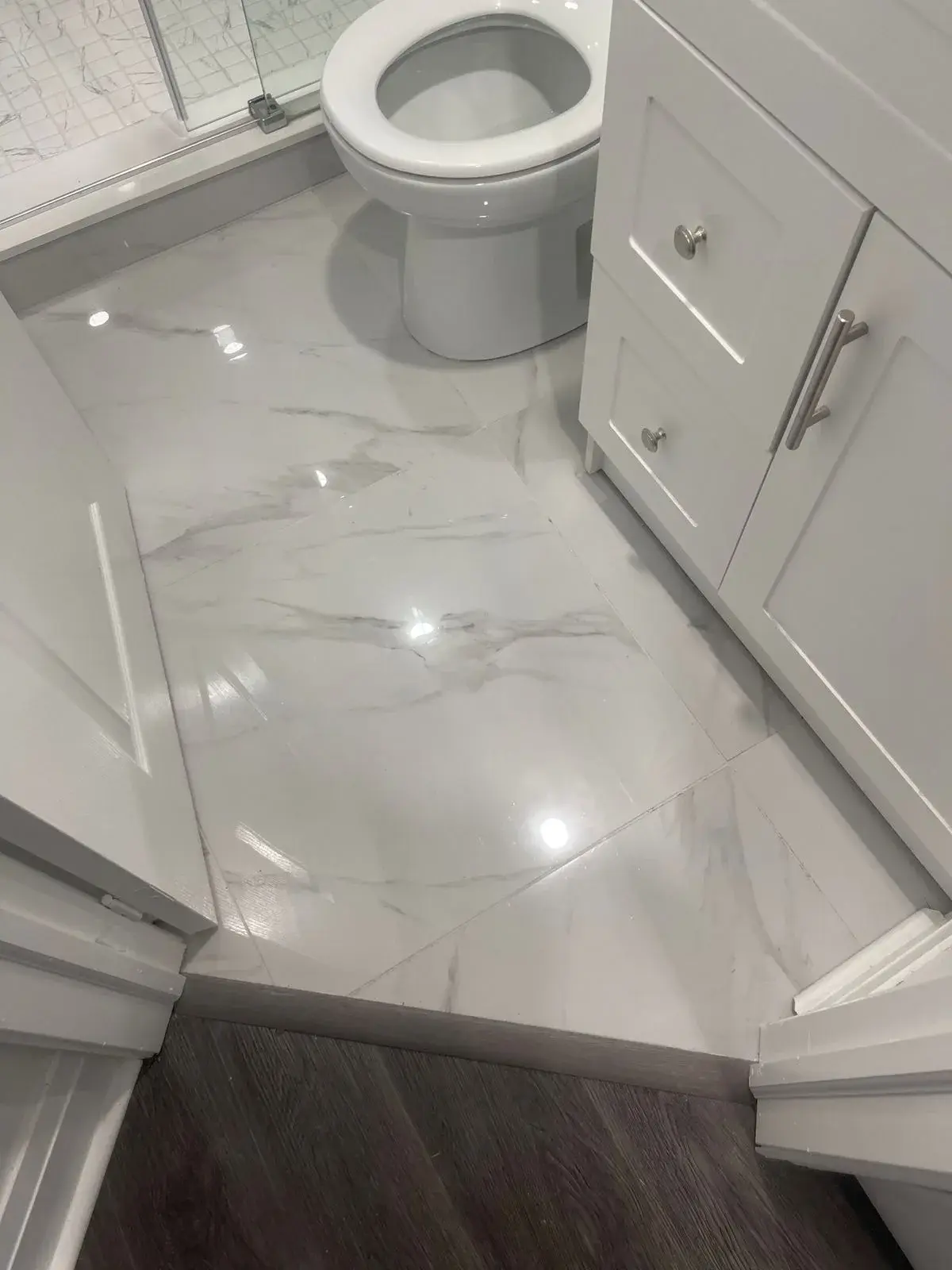 Porcelain bathroom tile meeting vinyl plank flooring at the doorway