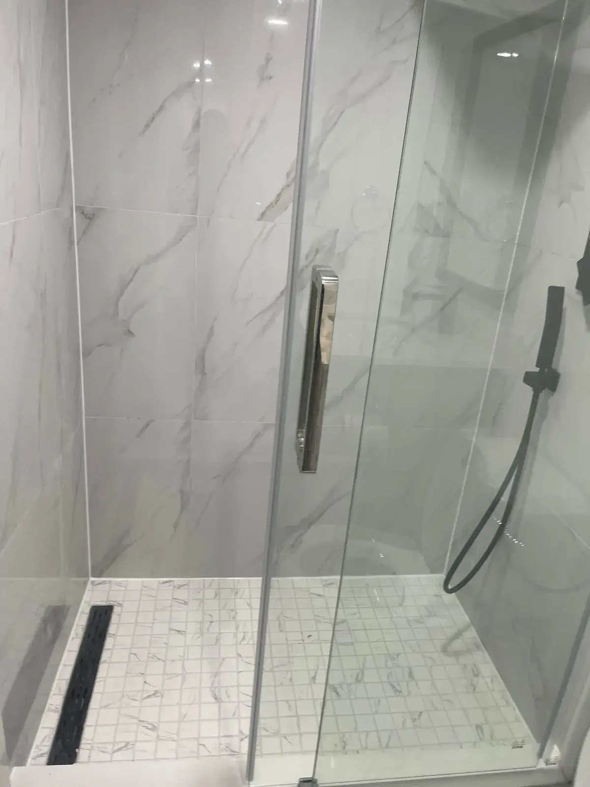 Tiled shower with a linear drain and marble-look porcelain walls