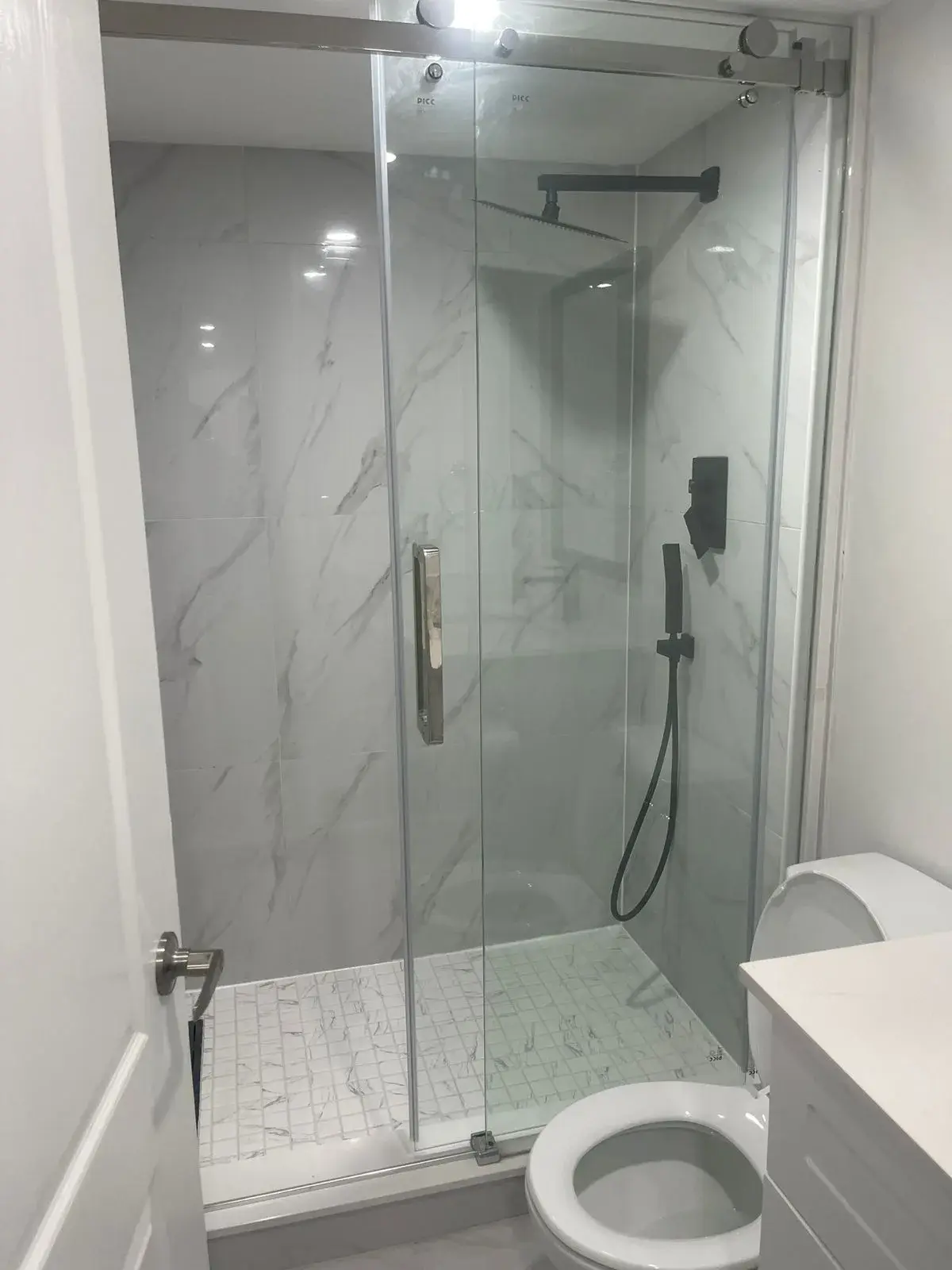 Shower with a sliding glass door and matte black fixtures