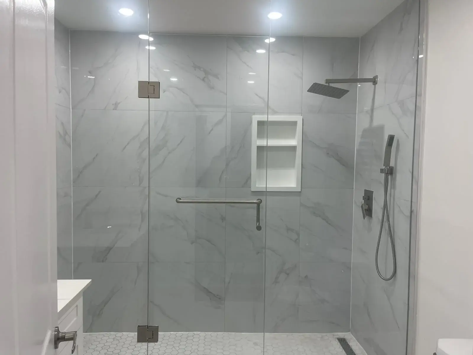 Walk-in shower with frameless glass, a rain shower head and a tiled niche