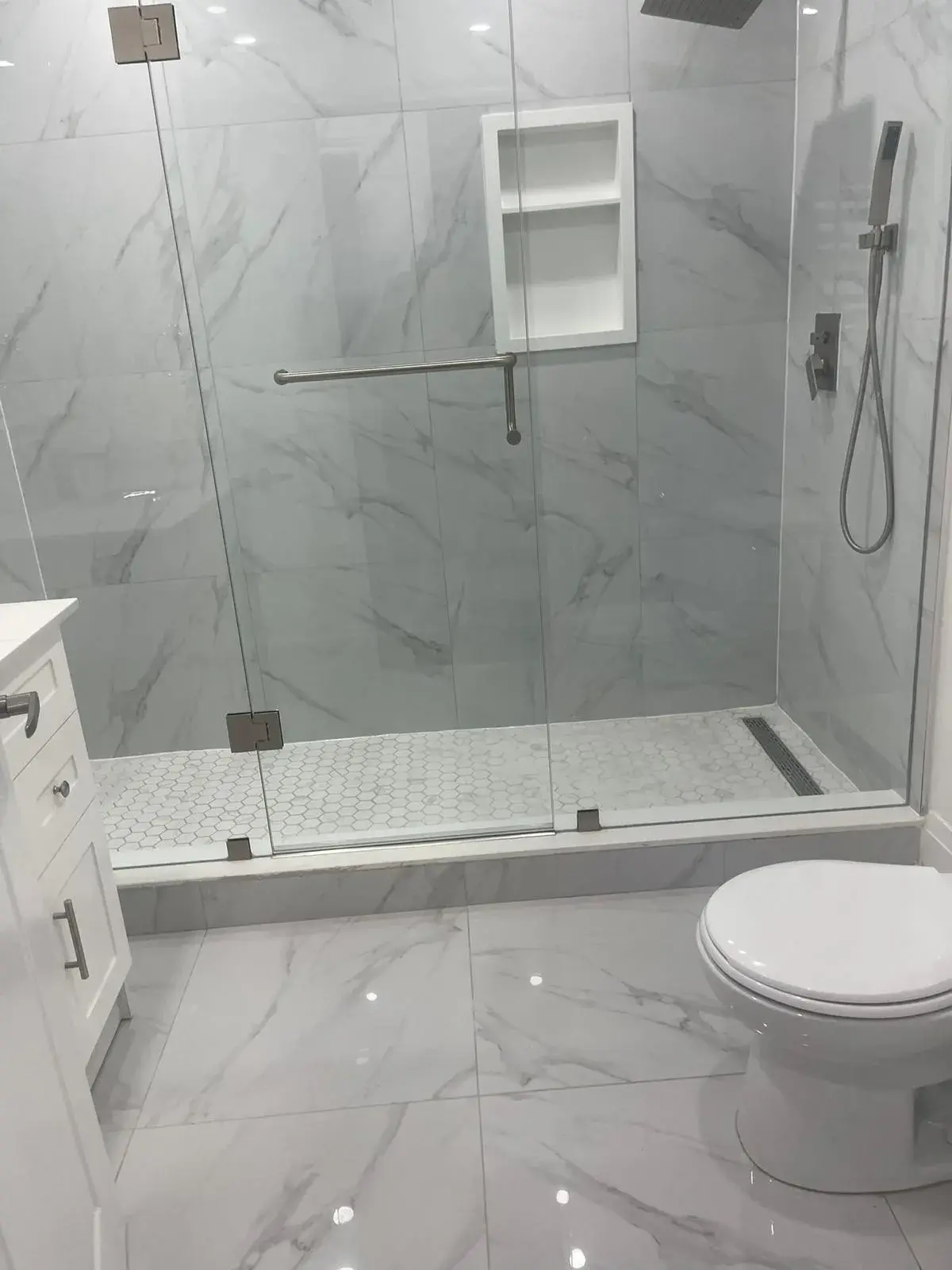 Walk-in shower with a recessed niche and a frameless glass panel